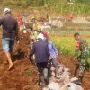 Babinsa Koramil Cilimus saat membantu warga membangun salurann irigasi.